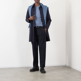 Model wearing navy overcoat with blue scarf, navy trousers, light blue top, and black leather loafers