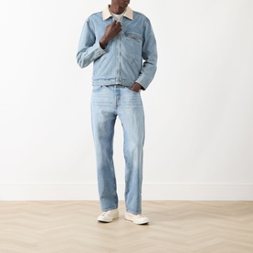 Model wearing Paige Laughlin Acid Wash Denim Jacket in Moby, light blue with contrast collar, styled with matching jeans and white trainers