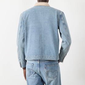 Model wearing Paige Laughlin Acid Wash Denim Jacket in Moby, showing back view with brushed twill collar and buttoned cuffs, styled with blue jeans.