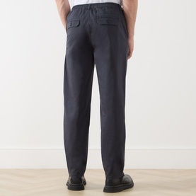 Model wearing Paige Eberton Tapered Leg Trousers in True Navy, rear view showing flap pockets and elasticated waistband, styled with black loafers.