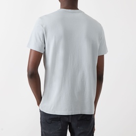 Model wearing Paige Sorden Solid T-Shirt in Bristol Blue, rear view. Crew neck, short sleeves, straight hem. Styled with dark jeans.