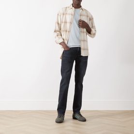 Model wearing Paige Sorden Solid T-Shirt in Bristol Blue, styled with a cream check overshirt and dark navy jeans.