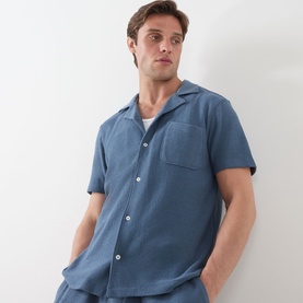 Model wearing Paige Oliver Patch Pocket Casual Shirt in Lakeside blue, short sleeves, camp collar, chest patch pocket, textured knit fabric