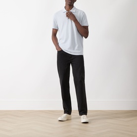 Model wearing Paige Demille Solid Polo Shirt in Bristol Blue Combo with black straight-leg trousers and white trainers.