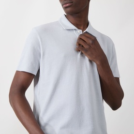 Model wearing Paige Demille Solid Polo Shirt in Bristol Blue Combo, piqu&eacute; cotton with flat collar and button fastening, short sleeves visible.