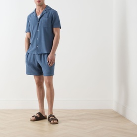 Model wearing Paige Elijah Hidden Drawstring Shorts in Lakeside blue, styled with matching textured shirt and tan sandals.