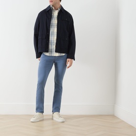 Model wearing Paige Flint Stone slim jeans with navy jacket, plaid shirt, and white trainers.