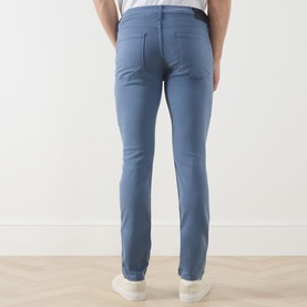 Model wearing Paige Slim Jeans in Flint Stone, rear view showing slim fit silhouette, styled with white trainers.