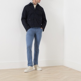 Model wearing Paige Slim Jeans in Flint Stone, styled with a navy jacket and white trainers