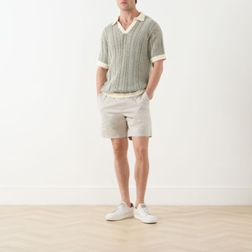 Model wearing Paige shorts in Shallow, styled with a green knit polo shirt and white trainers.