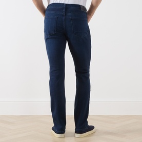 Model wearing Paige Pembry straight jeans in dark indigo wash, rear view, styled with cream trainers.