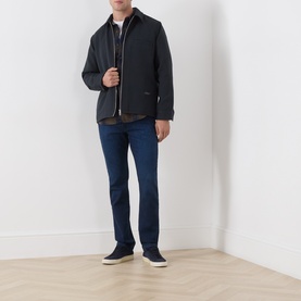 Model wearing Paige Pembry straight jeans in dark indigo, styled with a dark zip-up jacket and navy trainers.