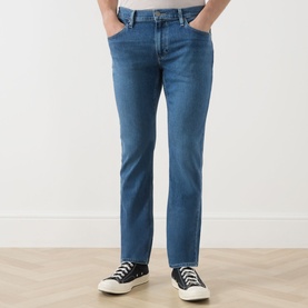 Model wearing Paige Straight Jeans in Bushman blue denim, styled with black and white canvas trainers.