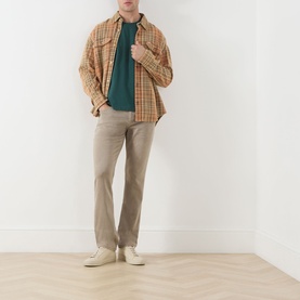 Model wearing Paige Federal Slim Straight Leg Jeans in Vintage Pale Beige, styled with orange check shirt, teal tee and cream shoes.