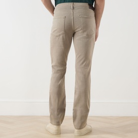 Model wearing Paige Federal Slim Straight Leg Jeans in Vintage Pale Beige, rear view, styled with white trainers and green top.