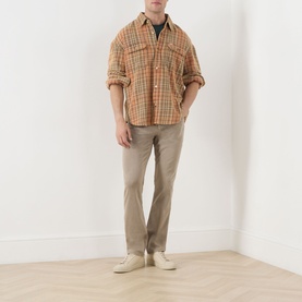 Model wearing Paige Federal Slim Straight Leg Jeans in Vintage Pale Beige, styled with an orange check overshirt and cream shoes.
