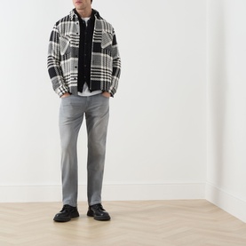 Model wearing Paige Wainwright straight jeans in grey, styled with a black and white plaid overshirt, white tee and black loafers.