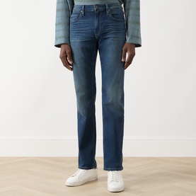Model wearing Paige Kirkwin straight jeans in mid-blue with faded wash detail, styled with white trainers and striped top.