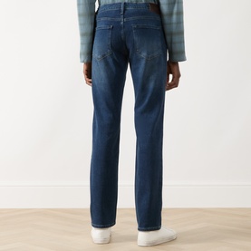 Model wearing Paige Kirkwin straight jeans in dark blue denim, rear view, styled with a plaid shirt and white trainers