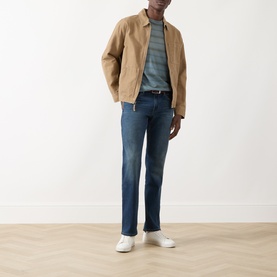 Model wearing Paige Kirkwin straight jeans in dark blue wash, styled with tan zip jacket, striped tee and white trainers.