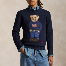 Model wearing Ralph Lauren navy knit jumper with Polo Bear holding US flag graphic, styled with chambray shirt and jeans