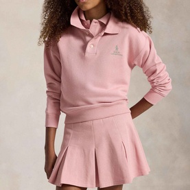 Model wearing Ralph Lauren Pony Logo Terry Polo Sweatshirt in Light Pink with pleated mini skirt. Long sleeves, ribbed collar, two-button placket.