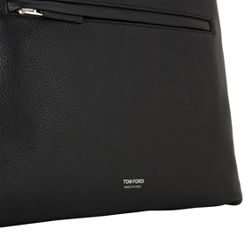 Tom Ford black leather backpack, close-up showing front zip pocket and silver-tone zip hardware with embossed logo detail.