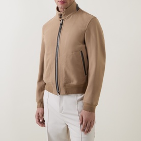 Model wearing Tom Ford Golden Brown wool-silk casual jacket with zip front, funnel neck, and ribbed hem, styled with white trousers.