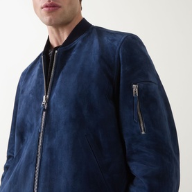 Model wearing Tom Ford indigo suede casual jacket with silver-tone zip detail and sleeve pocket, styled over black crew neck top.