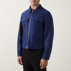 Model wearing Tom Ford navy cotton casual jacket with zip front, chest patch pockets and leather detail, styled with black trousers