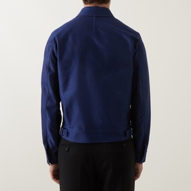 Model wearing Tom Ford navy cotton casual jacket, back view, with side buckle detail, styled with black trousers.