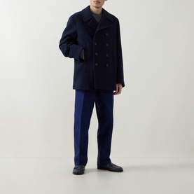 Model wearing Tom Ford navy wool coat with double-breasted buttons, styled with navy trousers and dark loafers.