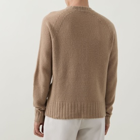 Model wearing Tom Ford Light Taupe cashmere crew neck sweater, back view, with white trousers.