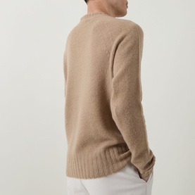Model wearing Tom Ford Light Taupe cashmere crew neck jumper, shot from behind, styled with white trousers.