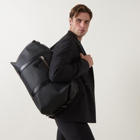Model carrying Tom Ford Grained Leather Holdall in black, worn over shoulder, silver-tone hardware, front zip pocket, textured calf leather finish