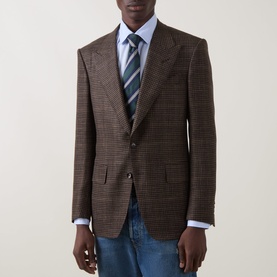 Model wearing Tom Ford black brown houndstooth wool blazer, styled with light blue shirt, striped tie and blue jeans.