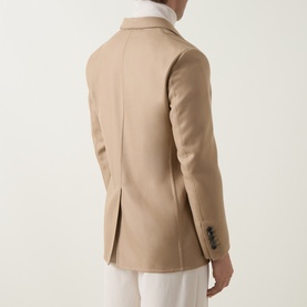Model wearing Tom Ford camel wool-silk blazer, back view, showing centre vent and three-button cuffs, styled with white shirt and trousers.