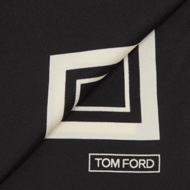 Tom Ford black silk pocket square with geometric square print in ivory, folded to show corner detail and branded label.