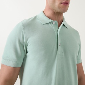 Model wearing Tom Ford Pique Regular Fit Polo Shirt in light green, showing polo collar, button placket and short sleeves in close-up crop
