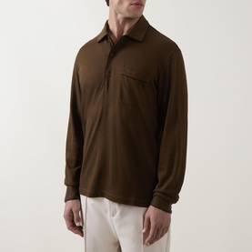Model wearing Tom Ford brown silk-cotton long-sleeve polo shirt with chest pocket and three-button placket, styled with cream trousers