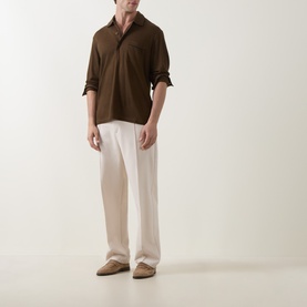 Model wearing Tom Ford brown silk-cotton polo shirt with cream wide-leg trousers and tan suede loafers.