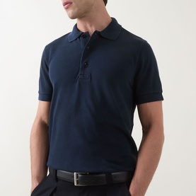 Model wearing Tom Ford Pique Regular Fit Polo Shirt in navy, short sleeves, button placket, styled with black trousers and belt.