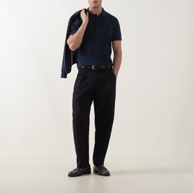 Model wearing Tom Ford Pique Regular Fit Polo Shirt in navy, styled with black tailored trousers, belt and loafers, carrying a jacket over shoulder.