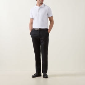 Model wearing Tom Ford white and black polo shirt with tipped collar, styled with black slim trousers and black leather shoes.