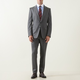 Model wearing Tom Ford grey wool suit with white shirt and striped tie, styled with dark brown oxford shoes.