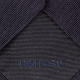 Tom Ford navy silk tie, close-up showing ribbed texture and embroidered logo detail on blade