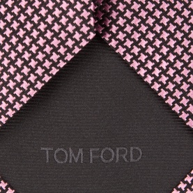 Tom Ford pink silk tie with black houndstooth pattern, showing embossed logo detail on dark reverse fabric