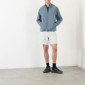 Model wearing 247 Dusky Navy casual nylon jacket with white shorts and dark trainers.