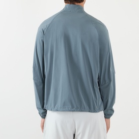 Model wearing 247 Casual Jacket in dusky navy, rear view, lightweight nylon with mock neck and raglan sleeves, styled with white shorts.