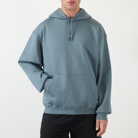 Model wearing 247 hoodie in dusky navy, relaxed fit with kangaroo pocket and drawstring hood, styled with black trousers